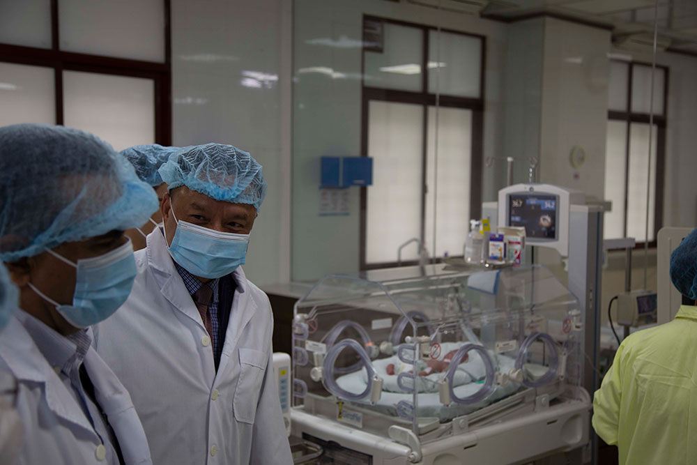 People wearing masks and lab coats in a lab.
