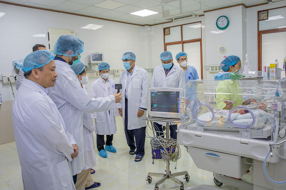 People in lab coats and masks in a lab.