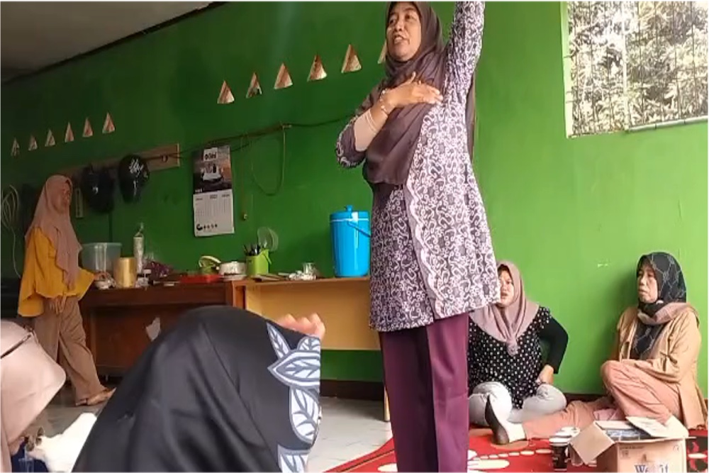 Woman talking to men in orange jumpsuits.