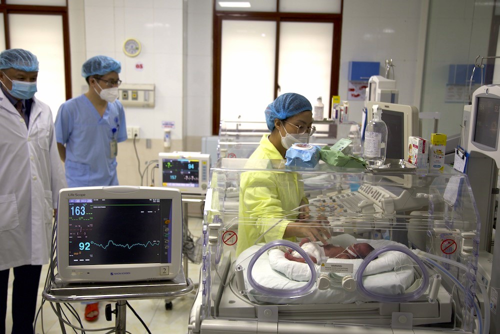 People in lab coats and masks in a lab.