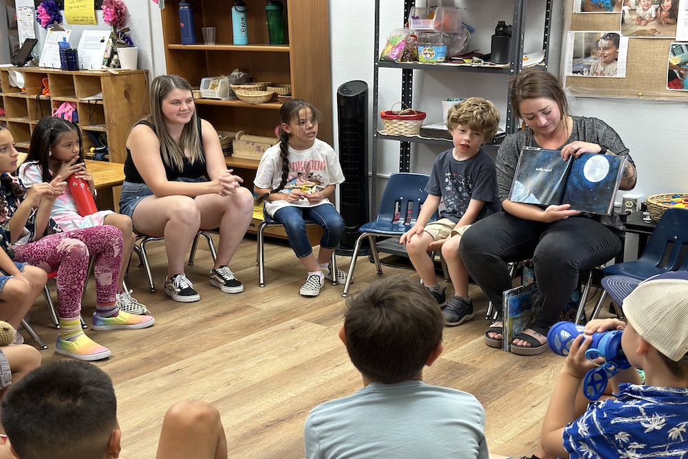 Two women, one looking through a microscope.
